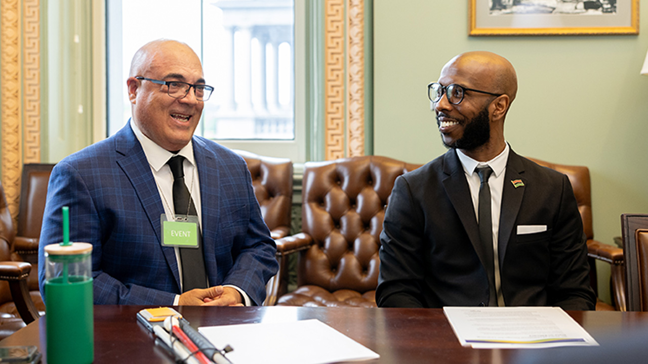 Photo of CAST disability expert Luis Perez speaking with teacher Brandon Woodland in a conference room at the White House